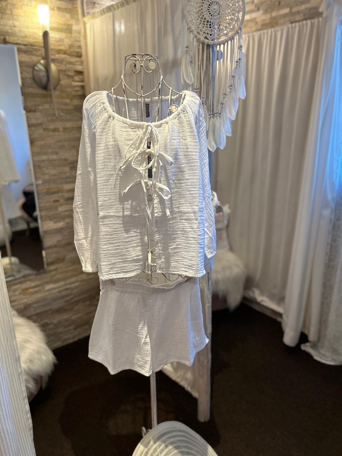 Eine weiße Bluse mit Schleifen und Shorts an einer dekorativen Schneiderpuppe im Boho-Stil